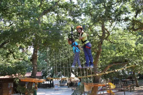 Bambini si divertono in un parco avventura Puglia, su un percorso sospeso tra gli alberi.