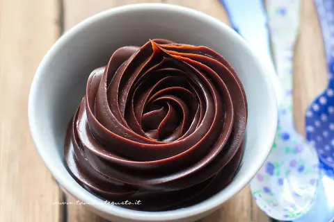 Una spirale perfetta di ganache cioccolato per copertura, lucida e invitante, in una ciotola bianca.