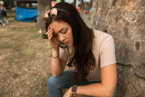 Vrouw met zonnebril op haar hoofd, hand op haar voorhoofd, lijkt te lijden aan een fobie voor naalden.