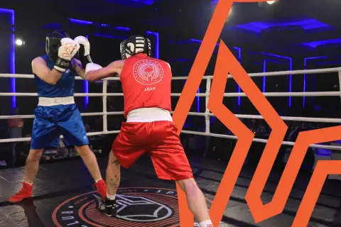 Two boxers in the lightest boxing weight class spar in a ring, one in blue, the other in red.