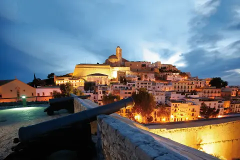 Alte Kanonen blicken auf die beleuchtete Altstadt von Ibiza im Winter.