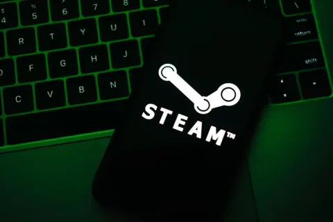 Telefon z logo Steam na tle zielonej klawiatury.