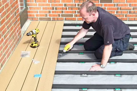 Man monterar komposittrall med skruvdragare. Ett vanligt problem med komposittrall är att det kan vara svårt att få jämna mellanrum.
