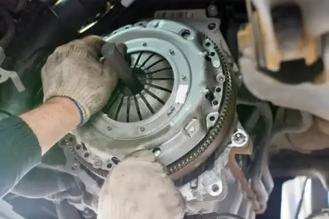 Mécanicien travaillant sur un embrayage. La question "combien de temps pour changer un embrayage" est souvent posée par les automobilistes.