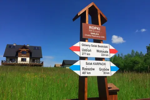 Rozdroże szlaków GSB i Karpackiego w Ropkach. Wskazówki pokazują kierunki do Ustronia, Wołosatego, Rzeszowa i Grybowa.
