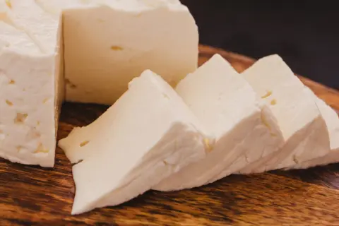 Queso de cabra fresco y cortado en cuñas sobre tabla de madera. Ideal para ensaladas, con pocas calorias.