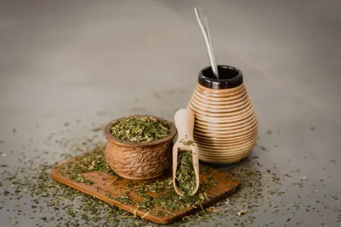 Naczynie z yerba mate i bombilla. Susz rozsypany na desce. Czy yerba mate ma właściwości negatywne?