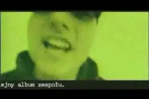 Fragment klipu zespołu Kaliber 44. Widać twarz rapera na zielonym tle. Tekst: "ejny album zespołu.