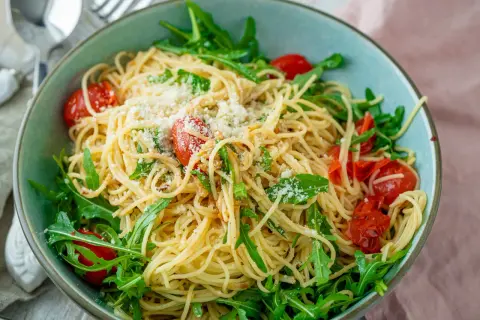 Spaghetti mit Rucola, Kirschtomaten und Parmesan in einer Schüssel.