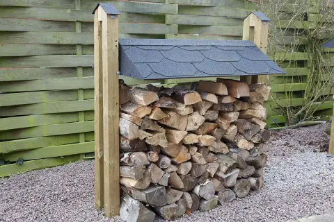 En stapel ved, redo för att bygga vedbod. Träet är torrt och fint staplat under ett tak.