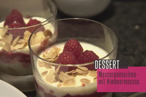 Zwei Gläser mit Himbeer-Mascarpone-Creme, garniert mit frischen Himbeeren und Mandelblättchen. Ein köstliches Dessert.