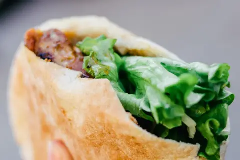 Kebab w bułce z mięsem i świeżą sałatą.