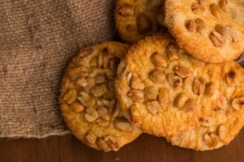 Knusprige erdnuss schoko cookies, verlockend auf Jute und Holz arrangiert.