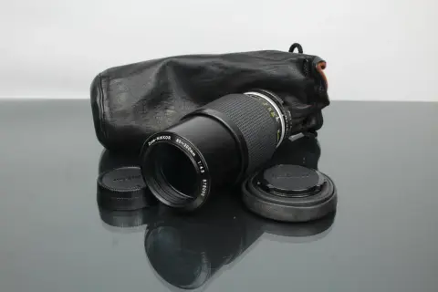 Objectif Zoom-NIKKOR 80-200mm f/4.5 avec son étui en cuir noir, prêt pour une nouvelle aventure photographique. Un classique Nikon.