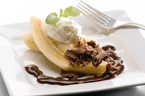 En bananhalva med vispgrädde, chokladspån och chokladsås. En klassisk banana split som ser utsökt ut.