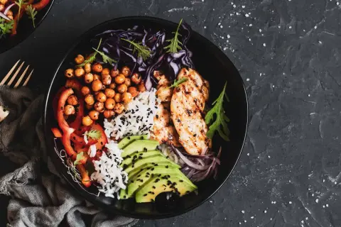 Un bol savoureux avec poulet grillé, riz, pois chiches, avocat et légumes. Parfait pour l'alimentation musculation.