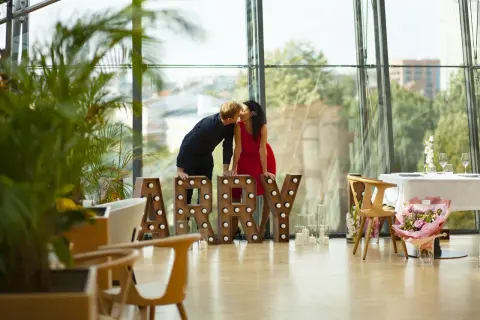 Para zapatrzona w siebie przy literach "MARRY" w nowoczesnym wnętrzu z widokiem na miasto. Idealne miejsce na zaręczyny Polska.