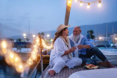 Ein glückliches Paar feiert seinen 44. Hochzeitstag auf einer Yacht. Die Bedeutung dieses Meilensteins wird durch ihre liebevolle Geste und die romantische Beleuchtung unterstrichen.