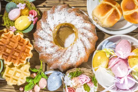 Kiedy jest śniadanie wielkanocne: babka, gofry, jajka w koszyczkach i bułeczki na drewnianym stole.