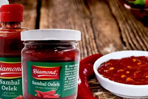 Słoiki z pikantnym sosem Sambal Oelek, z widocznymi papryczkami chili. Idealny do potraw, które potrzebują odrobiny ostrości.