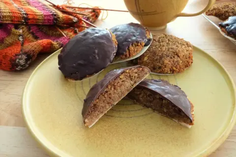 Schokoladen-Lebkuchen, ein köstliches Lebkuchen Rezept ohne Mehl, liegen auf einem Teller neben Strickzeug und einer Tasse.