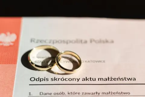 Złote obrączki na odpisie skróconym aktu małżeństwa. Dokument potwierdza zawarcie związku, jak wygląda akt ślubu.