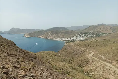 Vista panorámica de la costa de Almería, con el mar azul, un pueblo blanco y el paisaje árido del cerro negro.