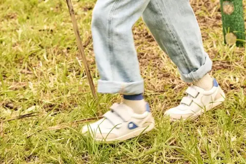 Białe sneakersy na rzepy, idealne na spacer po trawie. To wygodne buty dla aktywnych.