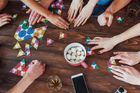 Hände legen bunte Spielsteine auf den Tisch. Ein gemütlicher Abend mit Zeit mit den liebsten Brettspiele.