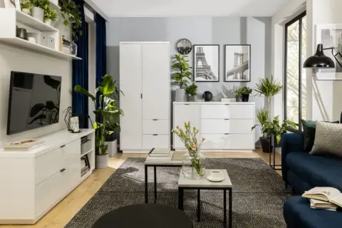 Nowoczesny salon z białymi meblami, granatową kanapą i mnóstwem zieleni. Inspiracja, jak ustawić kwiaty w salonie, by stworzyć przytulną atmosferę.