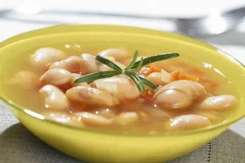 Zupa fasolowa przepis babci. Aromatyczna, sycąca, z dodatkiem rozmarynu, w żółtej miseczce.