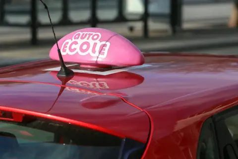 Voiture rouge d'auto-école, prête pour un jeune conducteur responsable qui vise le permis à 17 ans.