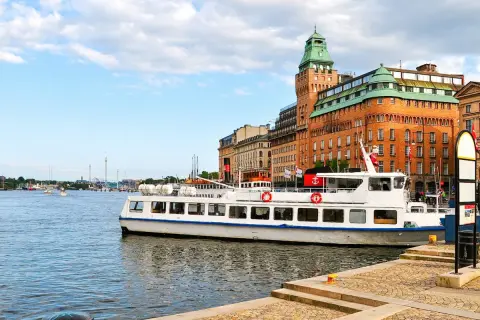 En vit passagerarbåt ligger vid kajen i Stockholm. En båttur här ger fin utsikt över stadens vackra byggnader och vattnet.