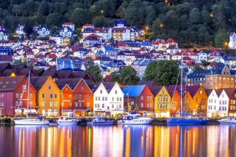 Bunte Holzhäuser am Wasser, ein Traum für Bergen Sightseeing. Boote spiegeln sich im Abendlicht.