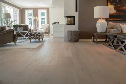 Amplio salón con chimenea y muebles elegantes, destacando los diversos tipos de parquet de madera clara que cubren el suelo.