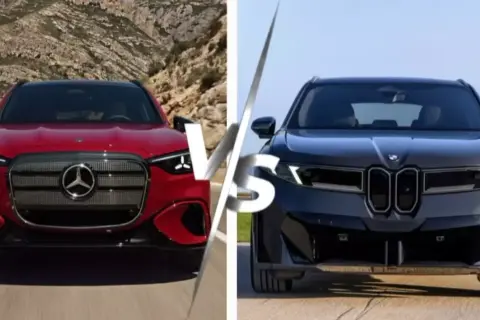 Czerwony mercedes sedan kontra ciemny BMW. Dwa luksusowe auta na tle górskiego krajobrazu i nieba.