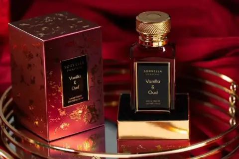 Eleganckie perfumy Sorvella Vanilla & Oud z ogonem, w bogatym, czerwonym opakowaniu, na złotym tle.
