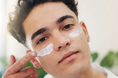 Mann trägt Gesichtscreme auf. SPF 15 Bedeutung: Schutz vor Sonneneinstrahlung für die Haut.