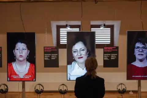 Eine Frau betrachtet drei Bildschirme mit Porträts von Frauen. Die Installation thematisiert die **Vergangenheit gegenwart** und individuelle Interviews aus Ost- und West-Berlin.
