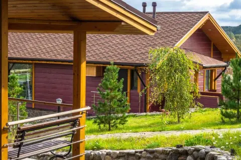 Drewniany domek z brązowym dachem i zielonym ogrodem.