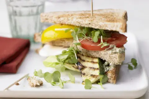 Ein saftiges, vegetarisches Sandwich mit gegrilltem Zucchini, Tomate, gelber Paprika und frischen Sprossen auf Vollkorntoast.