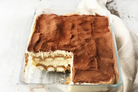 Pyszne tiramisu w szklanej formie, posypane kakao. Idealne, gdy wiesz, jak sparzyć jajka do tiramisu.