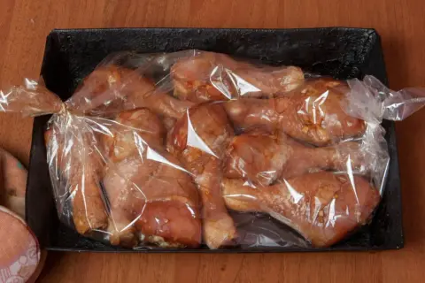 Pałki z kurczaka w rękawie, gotowe do pieczenia. Soczyste mięso w marynacie czeka na swoją kolej.
