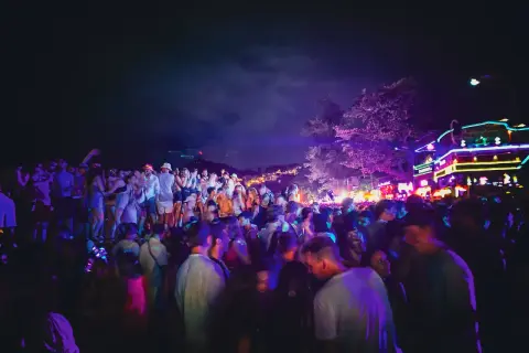 Stor folkmassa festar under neonljus på Koh Phangan, Thailand.