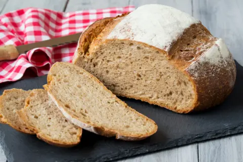 Chleb pełnoziarnisty, pokrojony w kromki, z mąką na wierzchu. Idealny na śniadanie, oto prosty chleb pełnoziarnisty przepis.