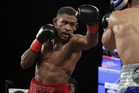Jacobs boxer, Daniel Jacobs, throws a punch during a boxing match, sweat glistening on his muscular physique.