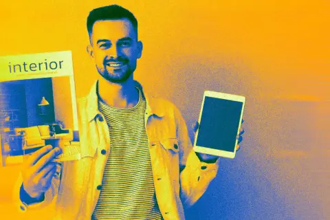 Un homme souriant présente un catalogue issuu sur l'intérieur et une tablette.