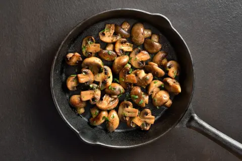 Stekta champinjoner i gjutjärnspanna, perfekt för ett snabbt svamp recept. Garnerade med persilja.