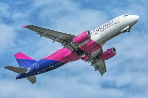 Samolot Wizzair z różowo-niebieskim malowaniem wznosi się na tle błękitnego nieba. Może to być symbol nadziei na nowy, odwołany lot Wizzair.