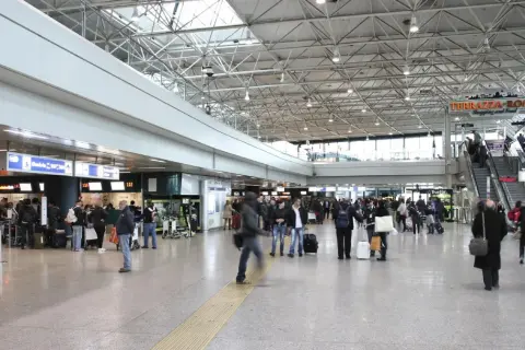 Tłoczny terminal lotniska Rome Ciampino, ludzie z bagażami czekają w kolejce do odprawy.